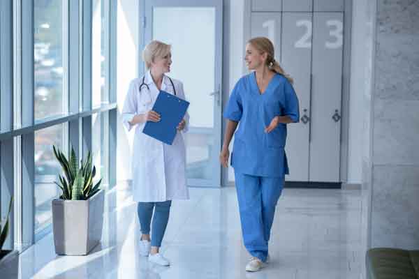 Two female doctors walking in a corridor having a conversation